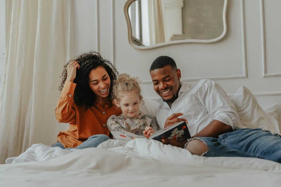 a family reading a book on the bed